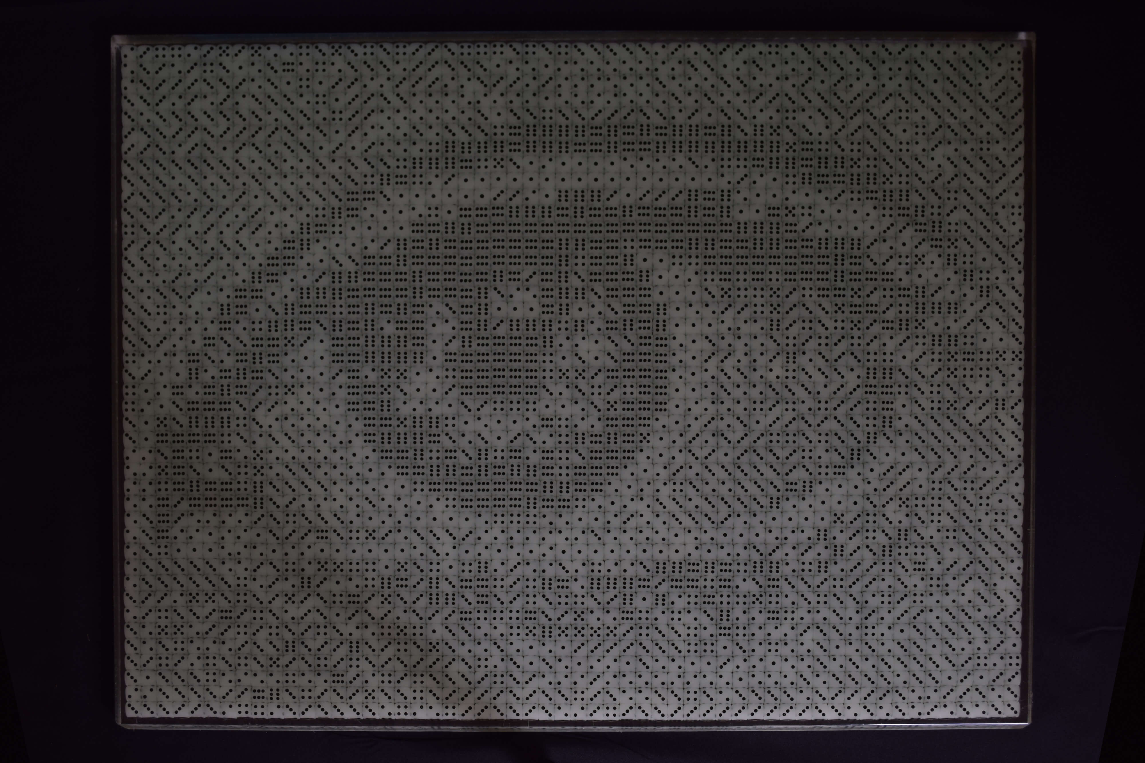 Dobbelstenenmozaïek van een vrouwenoog. De fosforescerende dobbelstenen hebben bij het daglicht een grijs-groene kleur en zwarte ogen.