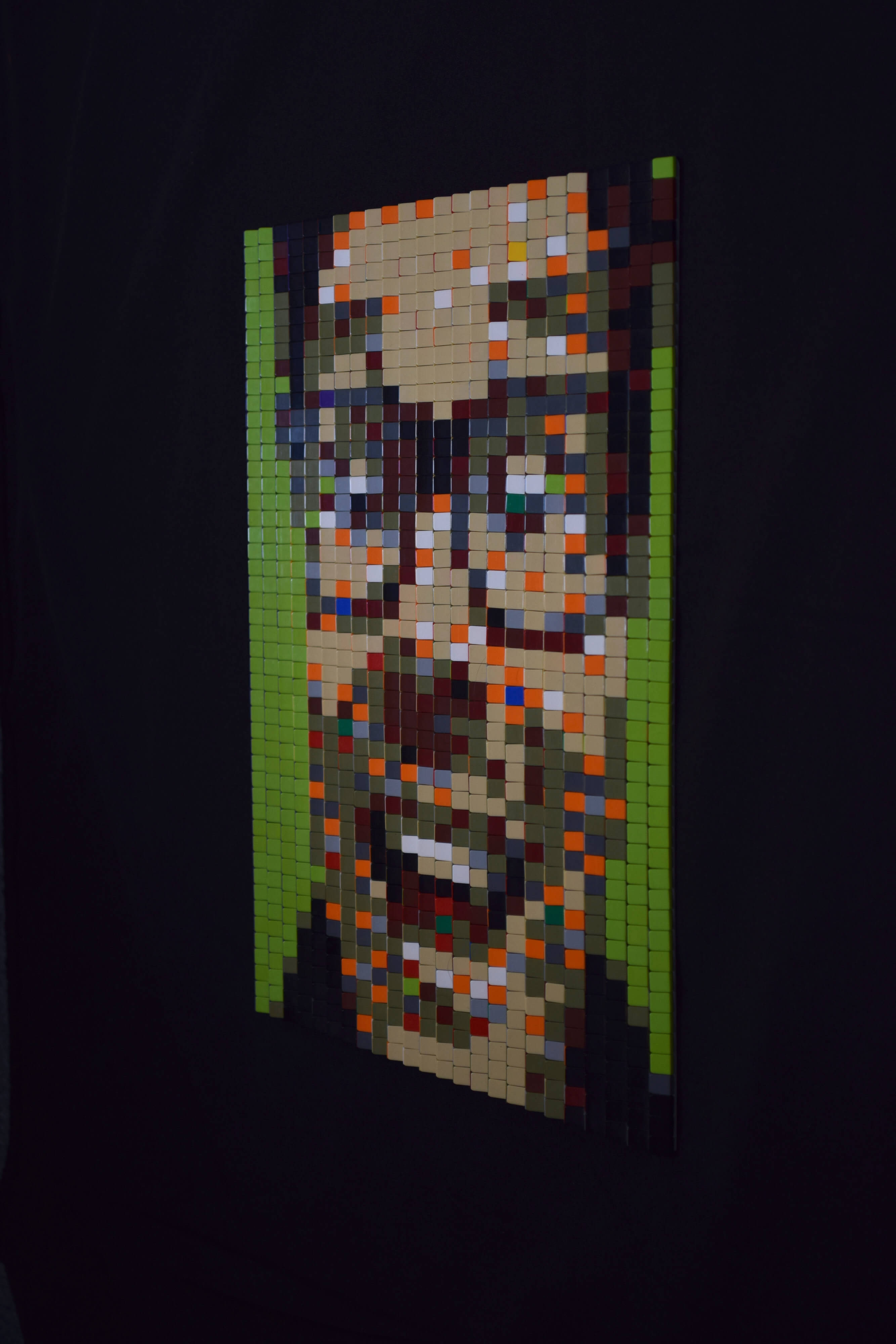 Zijaanzicht (links) van een tabula scalata van legosteentjes. Het kleurrijke portret van een lachende, brildragende man van middelbare leeftijd op een felgroene achtergrond.