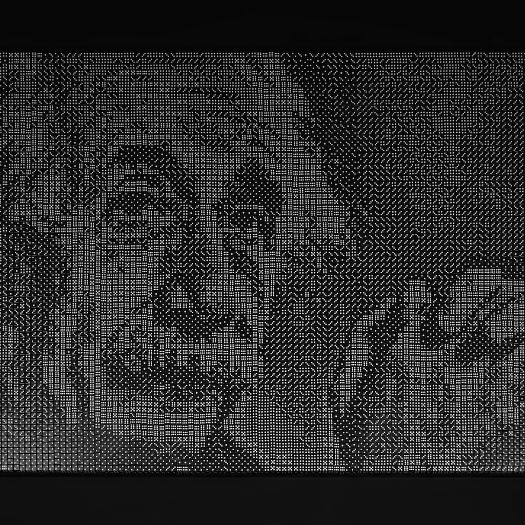 thumbnail - Een mozaïek van zwarte dobbelstenen met witte ogen op een zwarte achtergrond. Het mozaïek laat het gelaat en de gevouwen handen van Albert Einstein zien, die met een vriendelijke rustige blik de camera inkijkt.