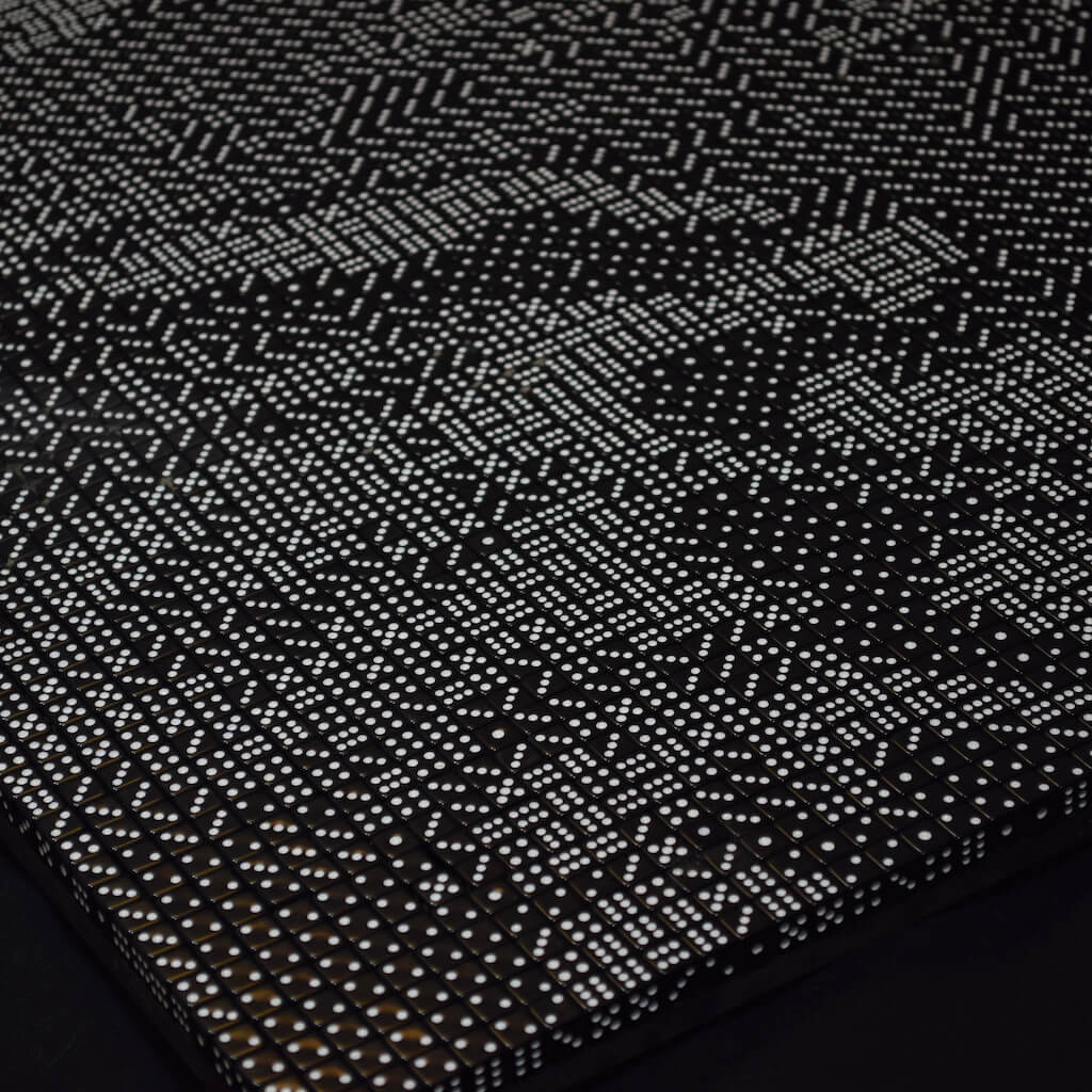 thumbnail - Detail van een dobbelstenenmozaïek waarop de gevouwen handen van een oudere man te zien zijn.