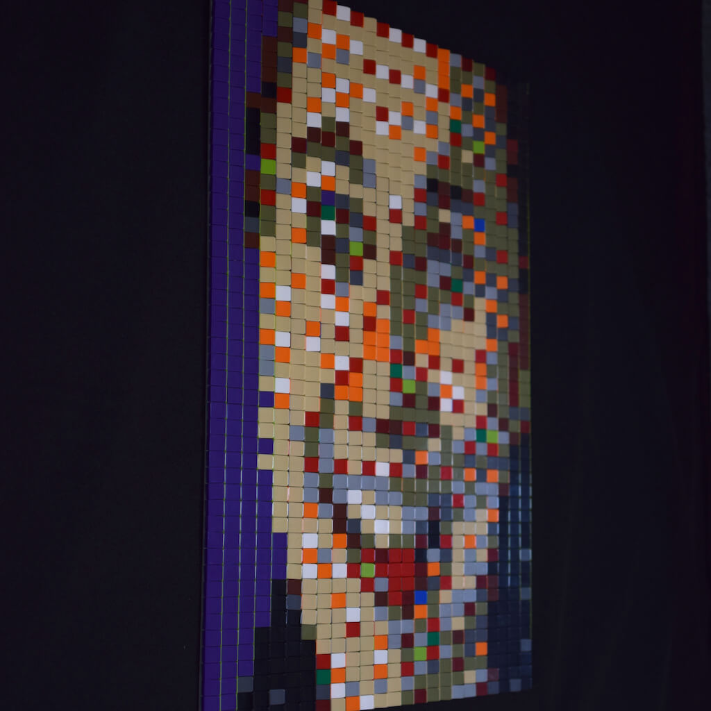 thumbnail - Zijaanzicht (rechts) van een tabula scalata van legosteentjes. Het kleurrijke portret van een lachende vrouw van middelbare leeftijd op een paarse achtergrond.